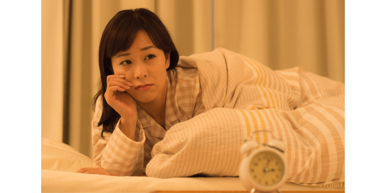 布団に入り眠れない女性
