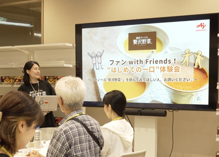 スクリーンに「ファン with Friends！“はじめての一口”体験会」を映し、社員がイベントの開会あいさつをする様子