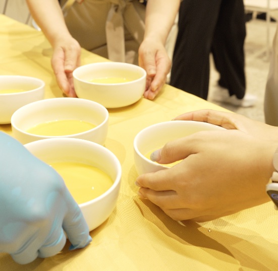 テーブルの上に並んだ「クノール®贅沢野菜®」今夏採れたてヌーヴォーコーンの器を、参加者が受け取る様子