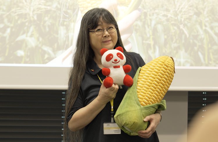 とうもろこしのクッションとアジパンダ®のぬいぐるみと一緒に記念撮影をする参加者さま